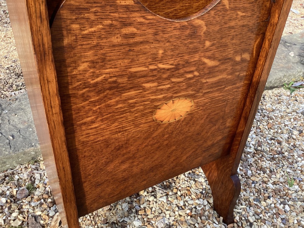 A floor-standing Edwardian oak magazine rack featuring three tiered sections, an integrated top handle aperture, and an oval marquetry shell inlay on the lower panel. View X