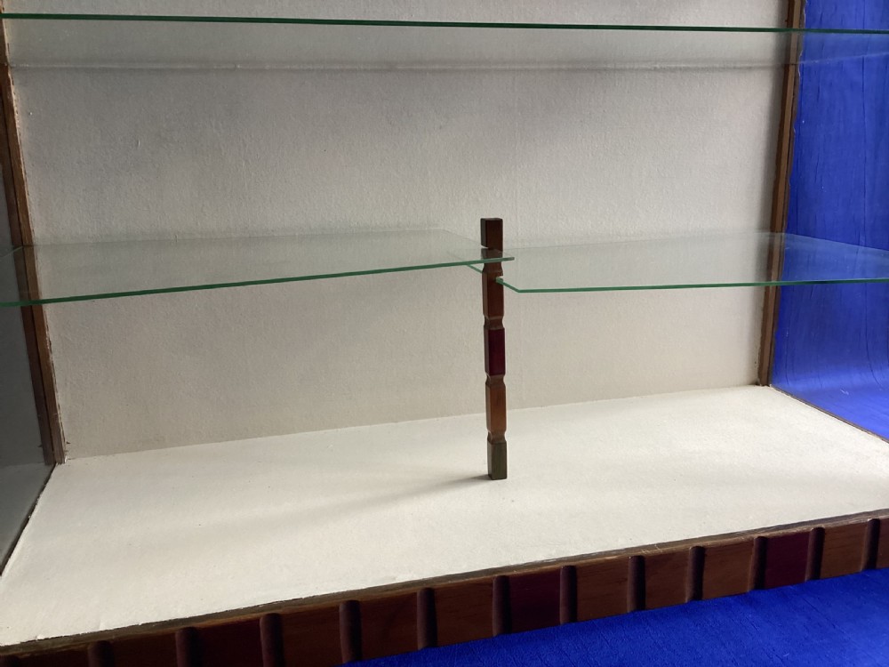 A rectangular Art Deco tabletop glass display case featuring notched wood framing and internal glass shelves. View II