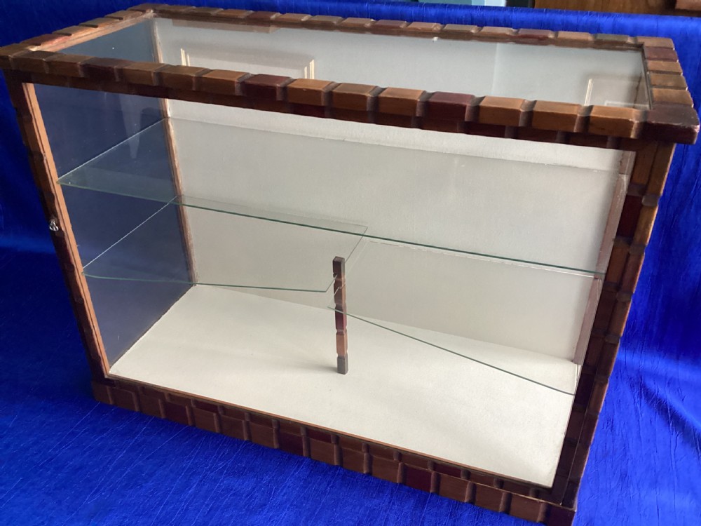 A rectangular Art Deco tabletop glass display case featuring notched wood framing and internal glass shelves. View IV