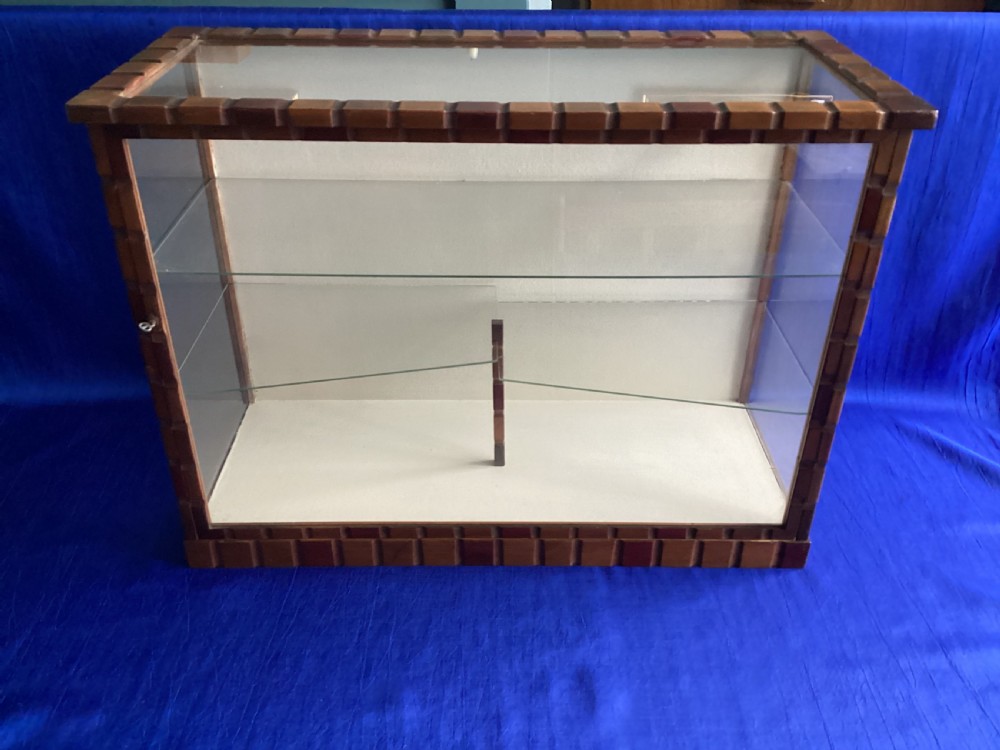 A rectangular Art Deco tabletop glass display case featuring notched wood framing and internal glass shelves. View XI