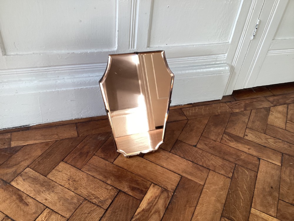 A frameless Art Deco easel vanity mirror made from peach-tinted glass with bevelled edges and chrome securing clips. View V