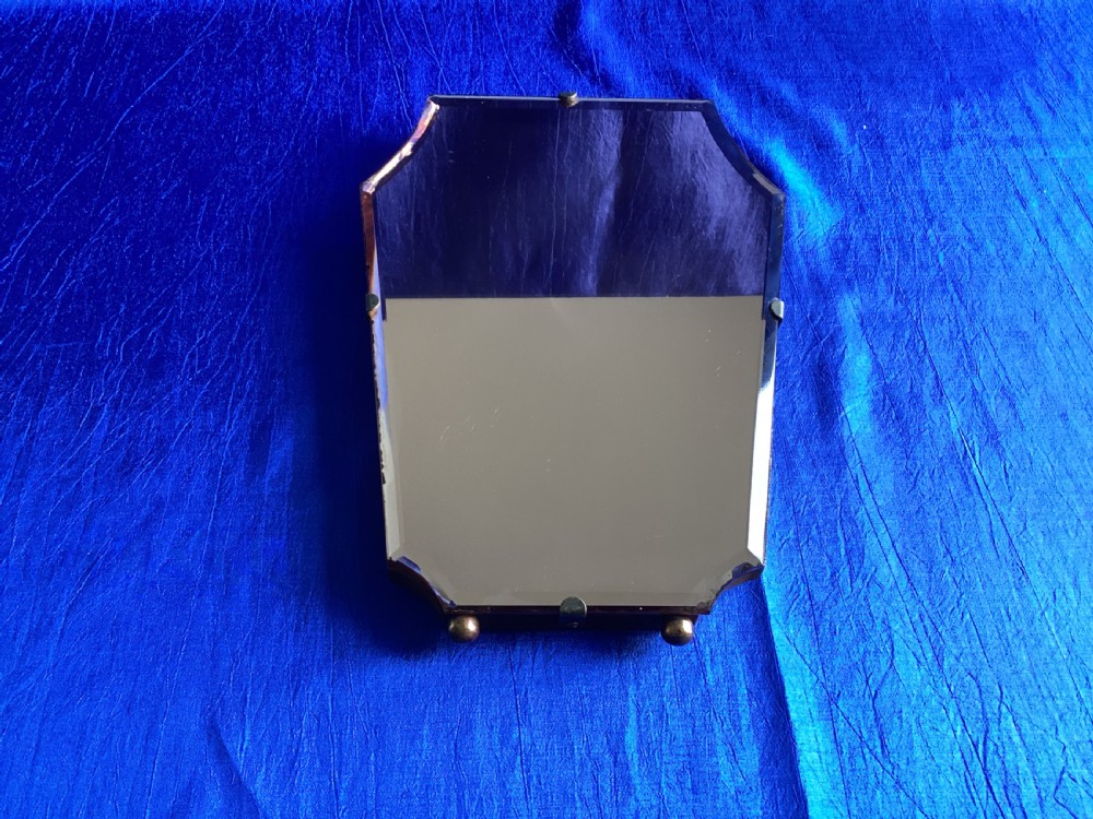 A frameless Art Deco easel vanity mirror made from peach-tinted glass with bevelled edges and chrome securing clips. View IX
