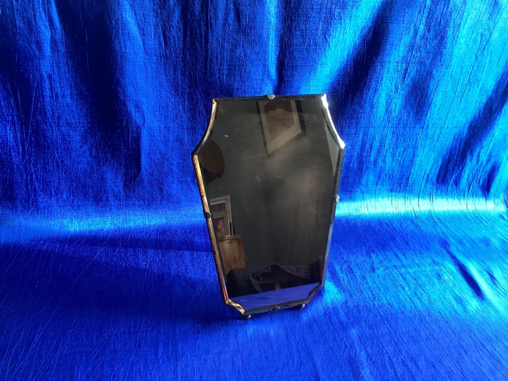 A frameless Art Deco easel vanity mirror made from peach-tinted glass with bevelled edges and chrome securing clips. View X