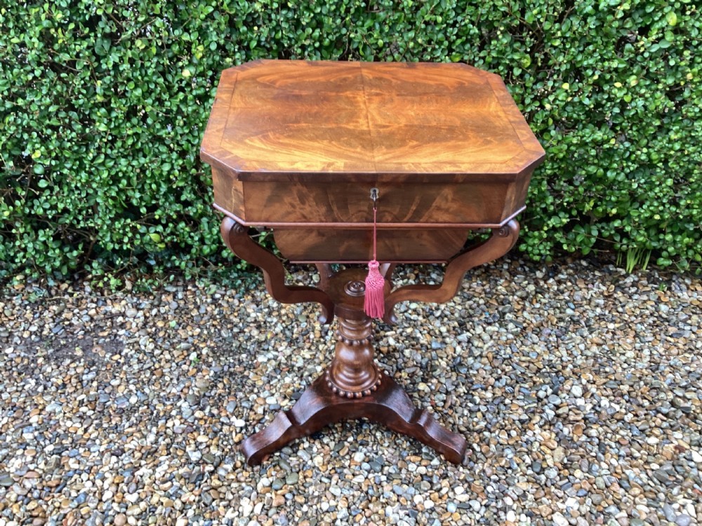 A Victorian flame mahogany sewing work table featuring a hinged top above a tapered work box, supported by curved S-scroll struts on a turned central pedestal with carved tripod legs. View III
