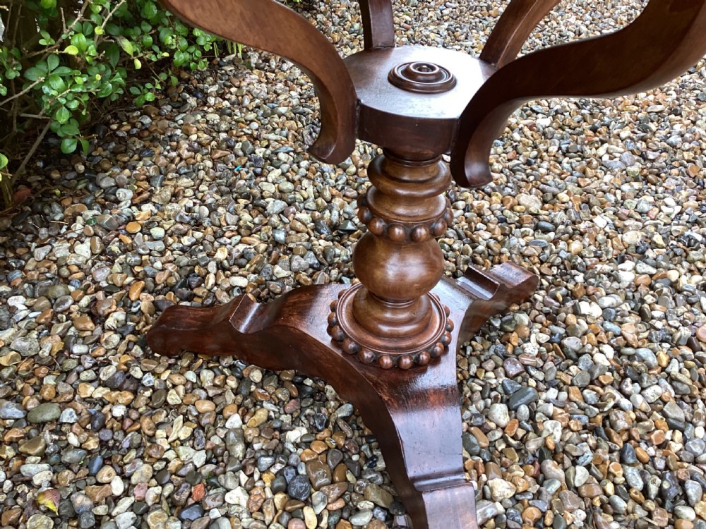A Victorian flame mahogany sewing work table featuring a hinged top above a tapered work box, supported by curved S-scroll struts on a turned central pedestal with carved tripod legs. View IV