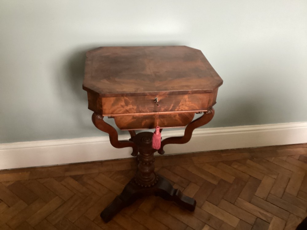 A Victorian flame mahogany sewing work table featuring a hinged top above a tapered work box, supported by curved S-scroll struts on a turned central pedestal with carved tripod legs. View XI