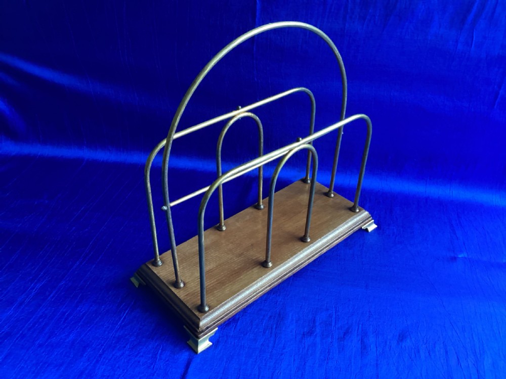 An Edwardian magazine rack featuring arched brass wire dividers mounted on a rectangular oak base with brass bracket feet. View II