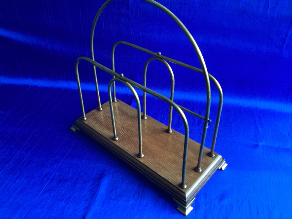 An Edwardian magazine rack featuring arched brass wire dividers mounted on a rectangular oak base with brass bracket feet. View III