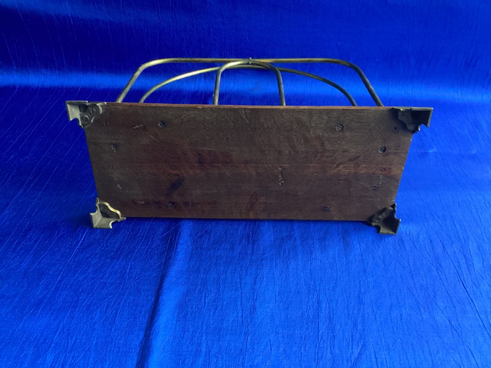 An Edwardian magazine rack featuring arched brass wire dividers mounted on a rectangular oak base with brass bracket feet. View IV