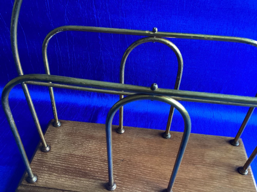 An Edwardian magazine rack featuring arched brass wire dividers mounted on a rectangular oak base with brass bracket feet. View V