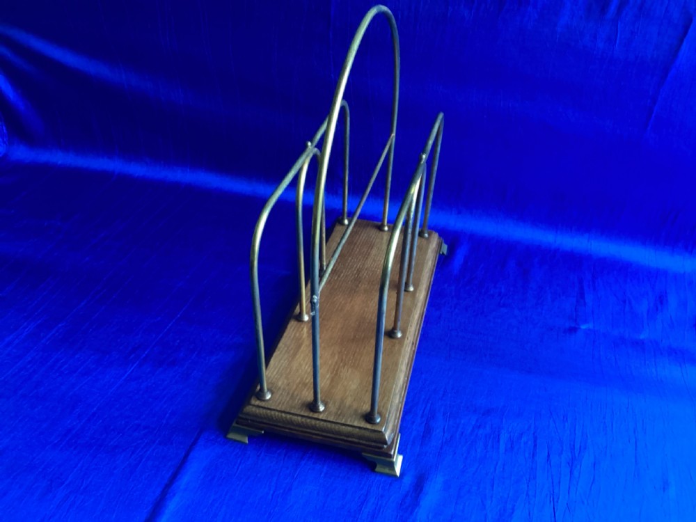 An Edwardian magazine rack featuring arched brass wire dividers mounted on a rectangular oak base with brass bracket feet. View VI