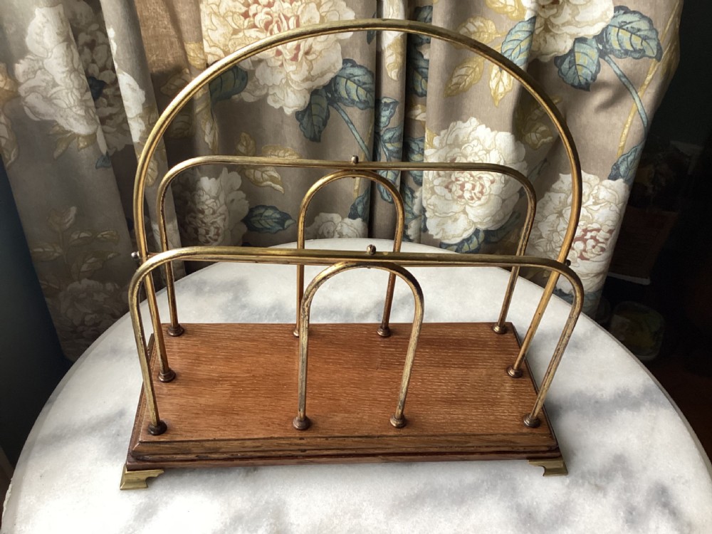 An Edwardian magazine rack featuring arched brass wire dividers mounted on a rectangular oak base with brass bracket feet. View VII