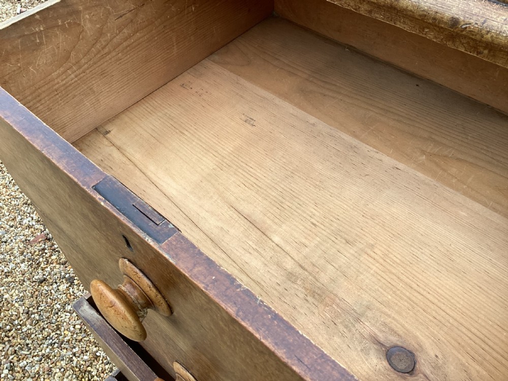 A Victorian pine chest of drawers featuring two short upper drawers over three long lower drawers, fitted with round turned wooden handles and short turned legs. View IX