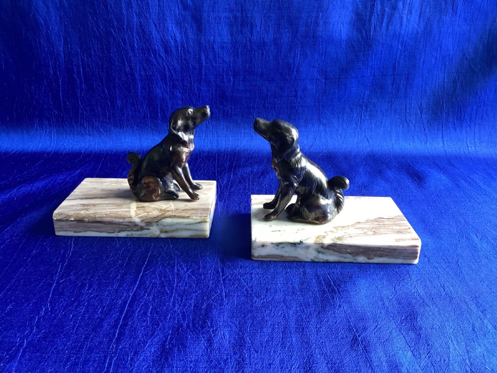 A pair of antique Art Deco bookends featuring patinated metal spaniel dogs sitting atop rectangular veined marble bases. View II