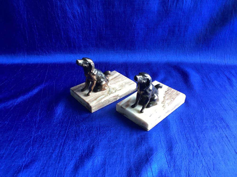 A pair of antique Art Deco bookends featuring patinated metal spaniel dogs sitting atop rectangular veined marble bases. View V