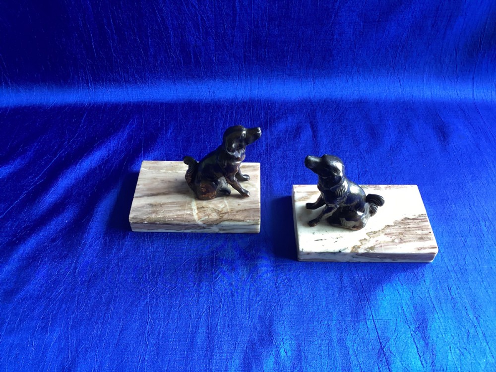 A pair of antique Art Deco bookends featuring patinated metal spaniel dogs sitting atop rectangular veined marble bases. View VI