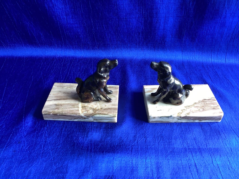A pair of antique Art Deco bookends featuring patinated metal spaniel dogs sitting atop rectangular veined marble bases. View IX