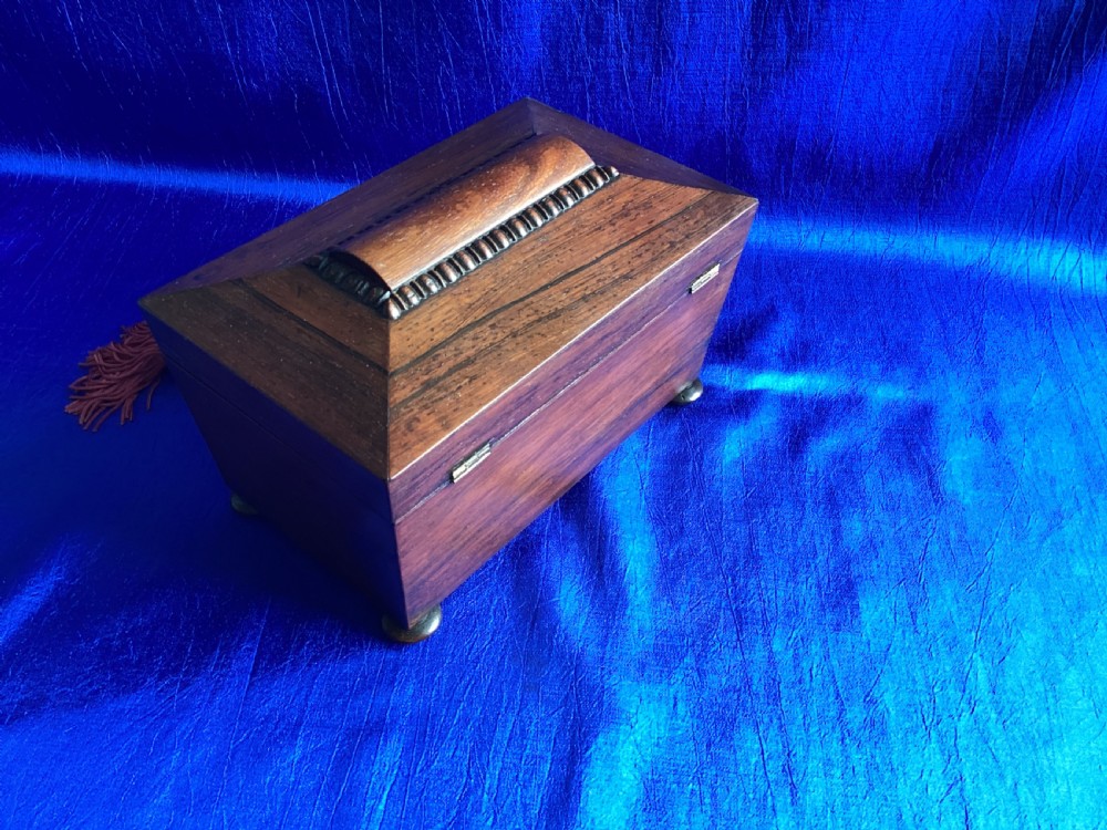 A Victorian rosewood tea caddy featuring a tapered sarcophagus lid with carved bead moulding, turned bun feet, and a central brass keyhole with a key and tassel. View III