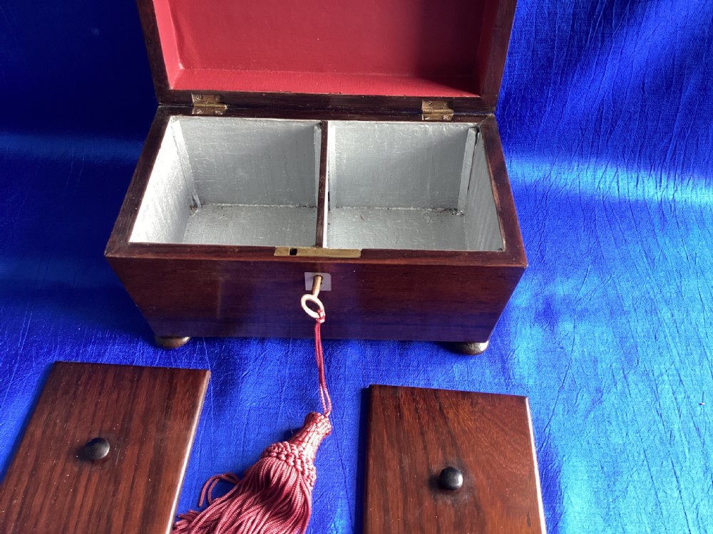 A Victorian rosewood tea caddy featuring a tapered sarcophagus lid with carved bead moulding, turned bun feet, and a central brass keyhole with a key and tassel. View V