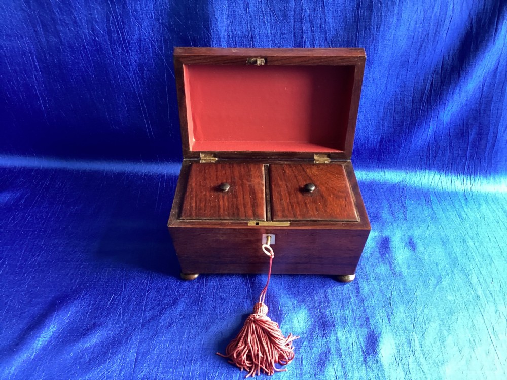 A Victorian rosewood tea caddy featuring a tapered sarcophagus lid with carved bead moulding, turned bun feet, and a central brass keyhole with a key and tassel. View VIII