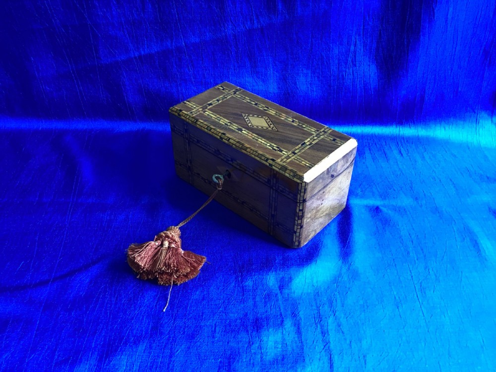 A rectangular Victorian walnut tea caddy featuring geometric parquetry inlaid borders, a central diamond-shaped keyhole escutcheon, and a key with a tassel. View III
