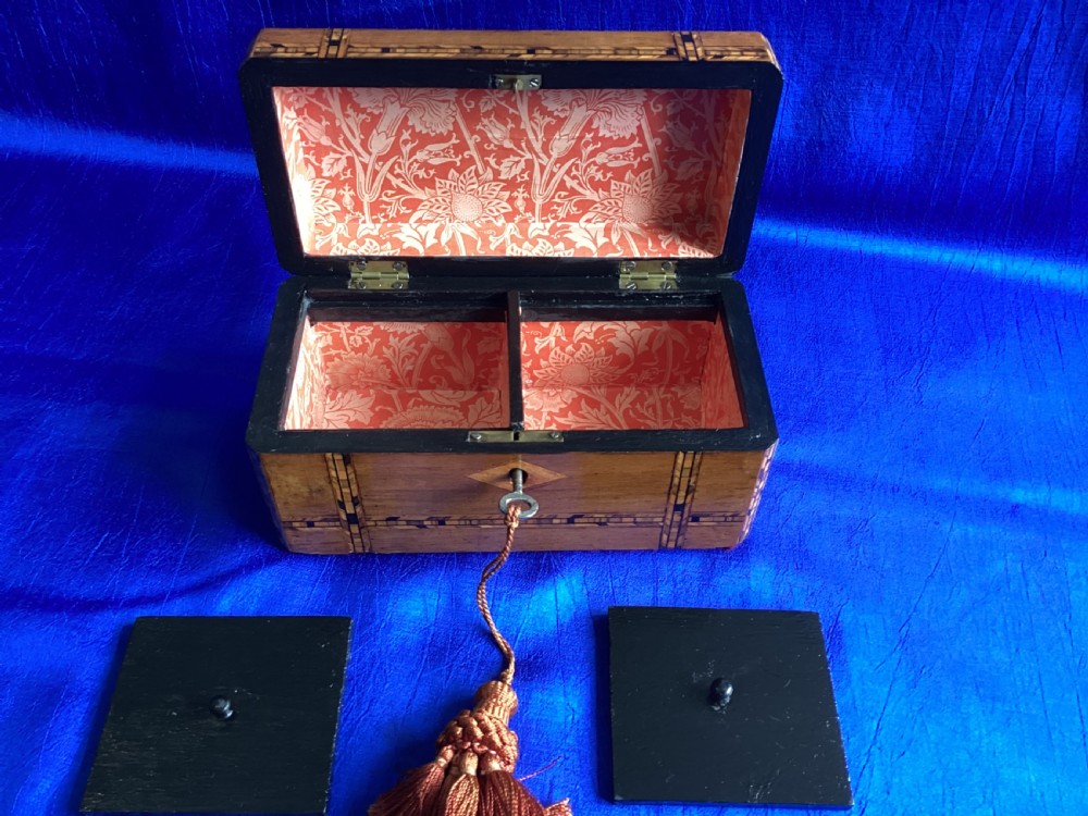 A rectangular Victorian walnut tea caddy featuring geometric parquetry inlaid borders, a central diamond-shaped keyhole escutcheon, and a key with a tassel. View VIII