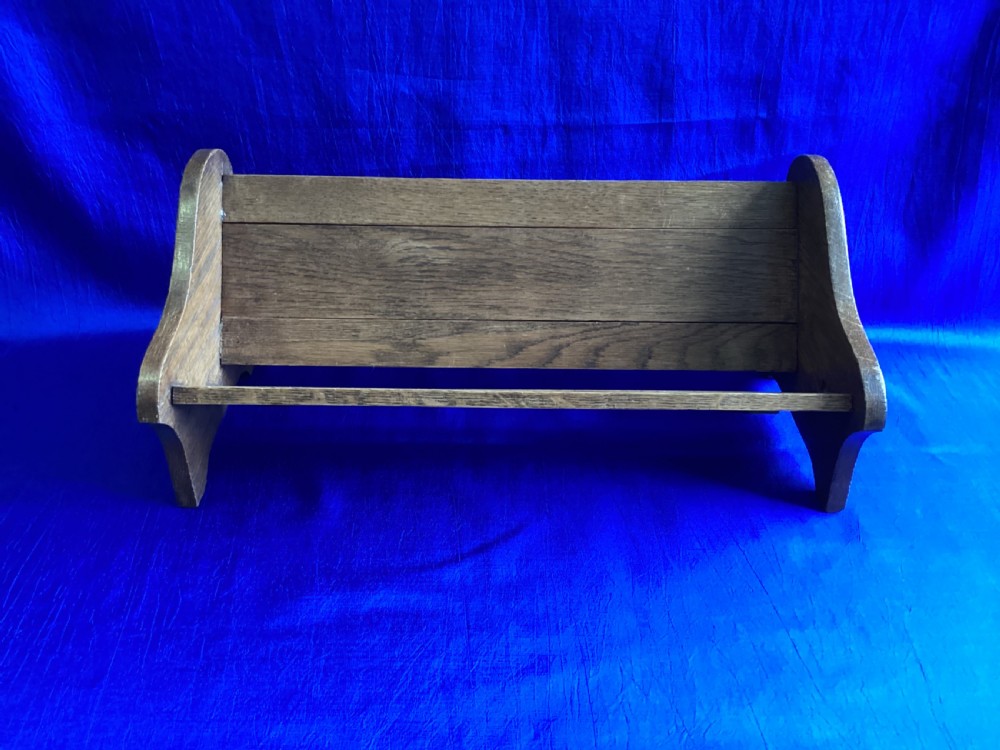 An Edwardian medium brown oak book slide featuring shaped end supports and an adjustable sliding base board.