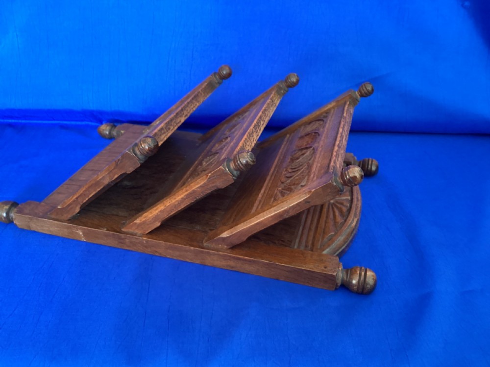 A carved oak desk letter rack featuring three tiered compartments, turned corner finials, and arched decorative carving. View V