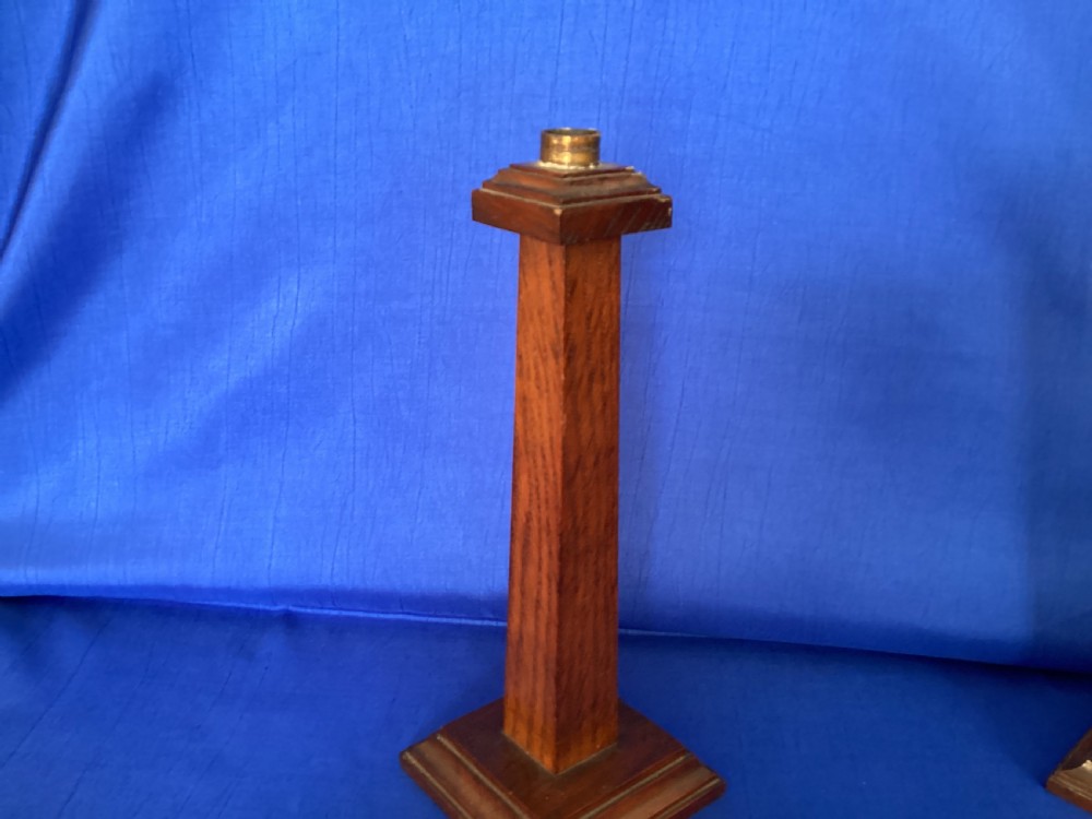 A pair of Edwardian Arts and Crafts tall oak candlesticks featuring square tapered shafts, stepped plinth bases, and brass nozzle inserts. View IV