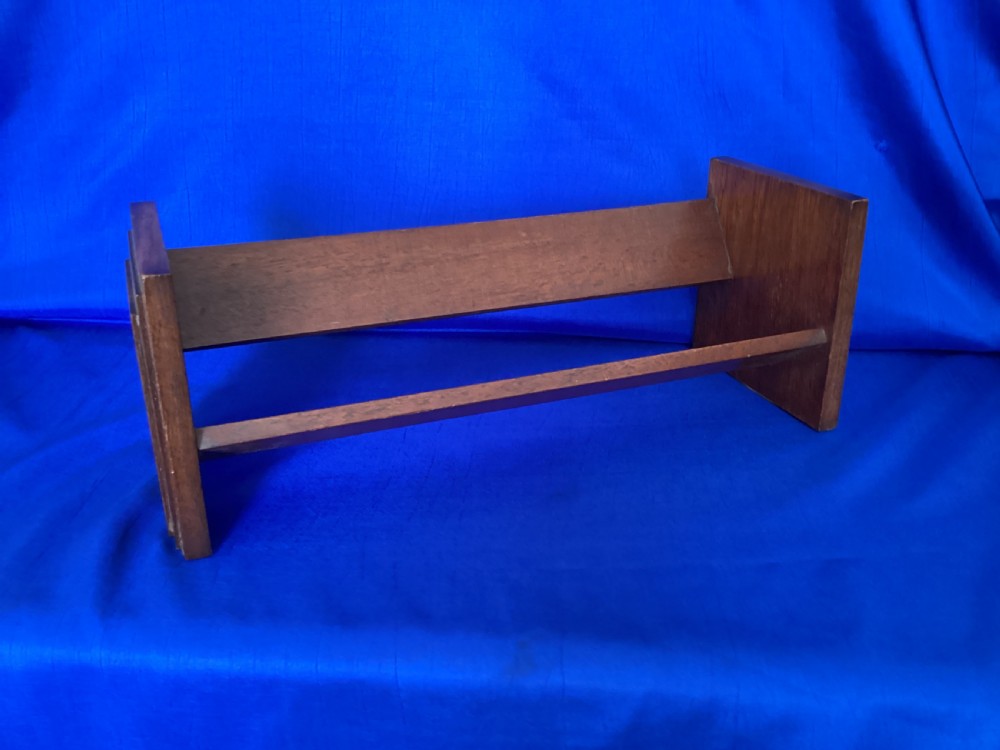 A dark mahogany wooden book trough featuring angled shelf boards and rectangular side supports. View II