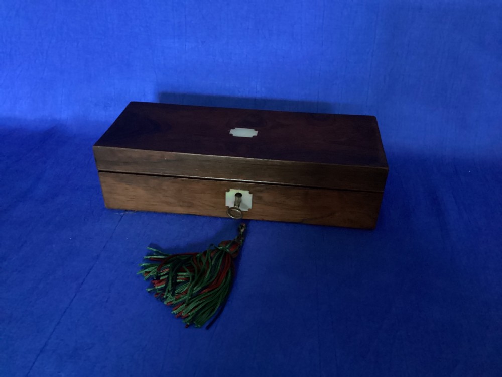 A rectangular Victorian dark rosewood glove box with a mother-of-pearl cartouche inlay on the lid and a matching keyhole escutcheon on the front. View V
