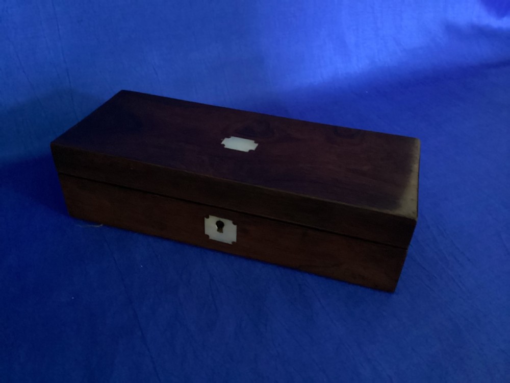 A rectangular Victorian dark rosewood glove box with a mother-of-pearl cartouche inlay on the lid and a matching keyhole escutcheon on the front. View VI
