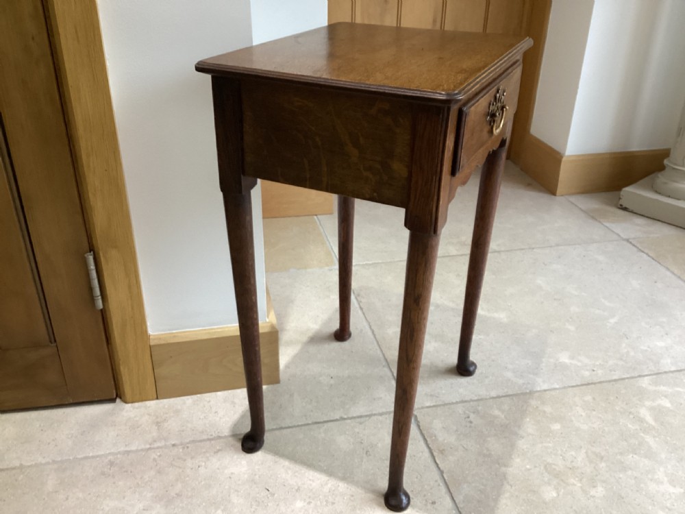 A Georgian country oak side table featuring a single drawer with a brass handle, shaped apron, and four tapered legs ending in pad feet. View III