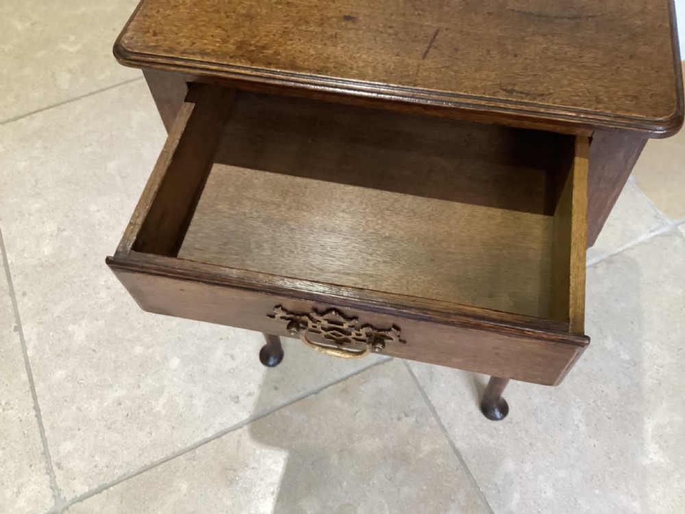 A Georgian country oak side table featuring a single drawer with a brass handle, shaped apron, and four tapered legs ending in pad feet. View IV