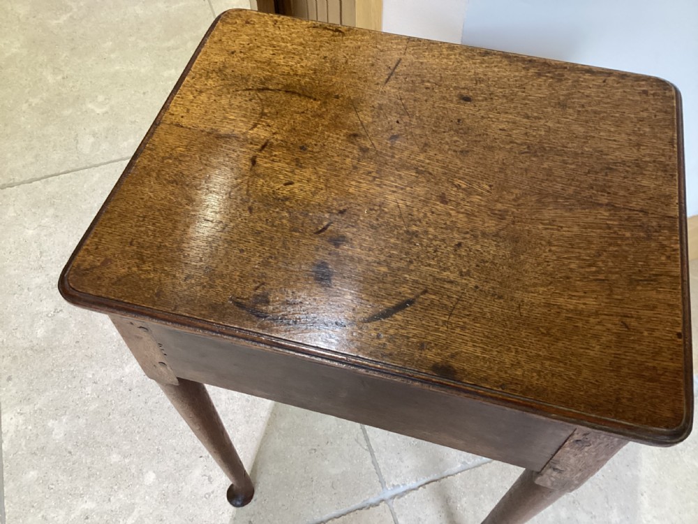 A Georgian country oak side table featuring a single drawer with a brass handle, shaped apron, and four tapered legs ending in pad feet. View VII