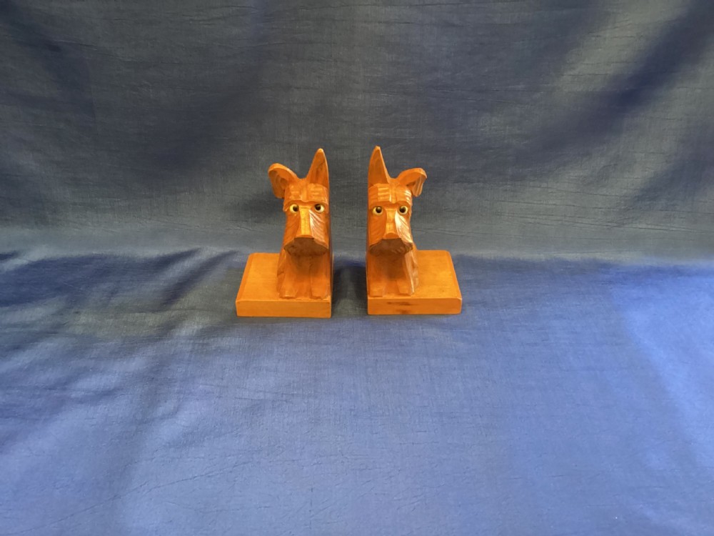 A pair of hand-carved wooden bookends shaped like Scottish Terriers with inset glass eyes on rectangular bases. View II