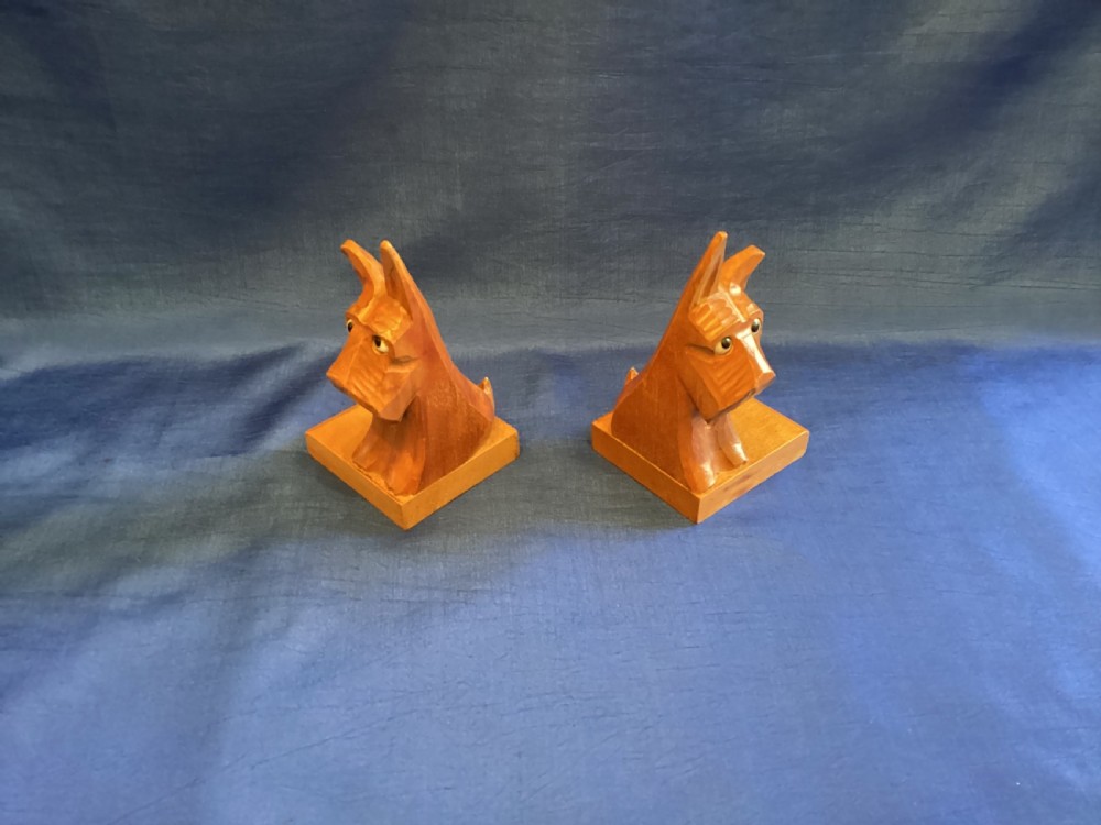 A pair of hand-carved wooden bookends shaped like Scottish Terriers with inset glass eyes on rectangular bases. View III