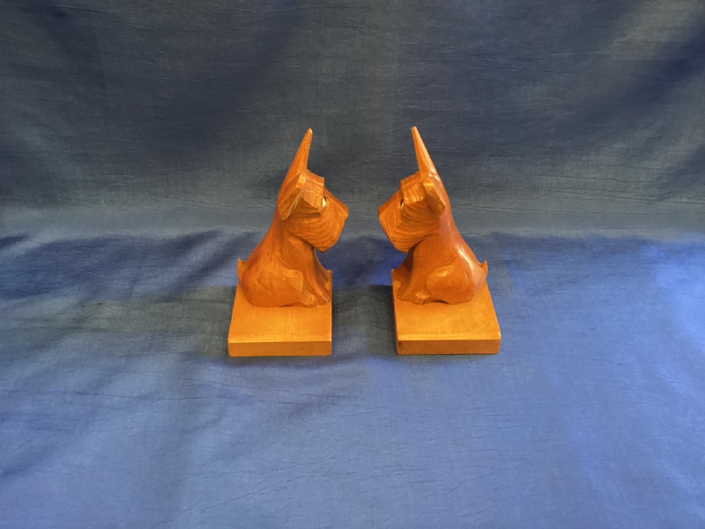 A pair of hand-carved wooden bookends shaped like Scottish Terriers with inset glass eyes on rectangular bases. View V