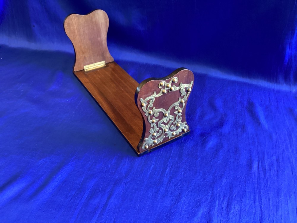 A dark mahogany extending book rest featuring decorative pierced brass scrollwork end panels with stud embellishments. View II
