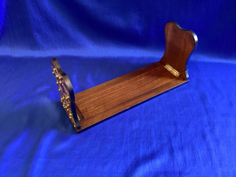 A dark mahogany extending book rest featuring decorative pierced brass scrollwork end panels with stud embellishments. View VI