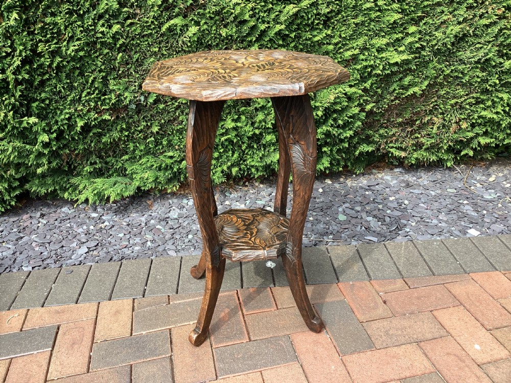 An antique dark wood octagonal side table featuring carved leaf patterns across the top surface, curved legs, and a lower tier shelf. View II
