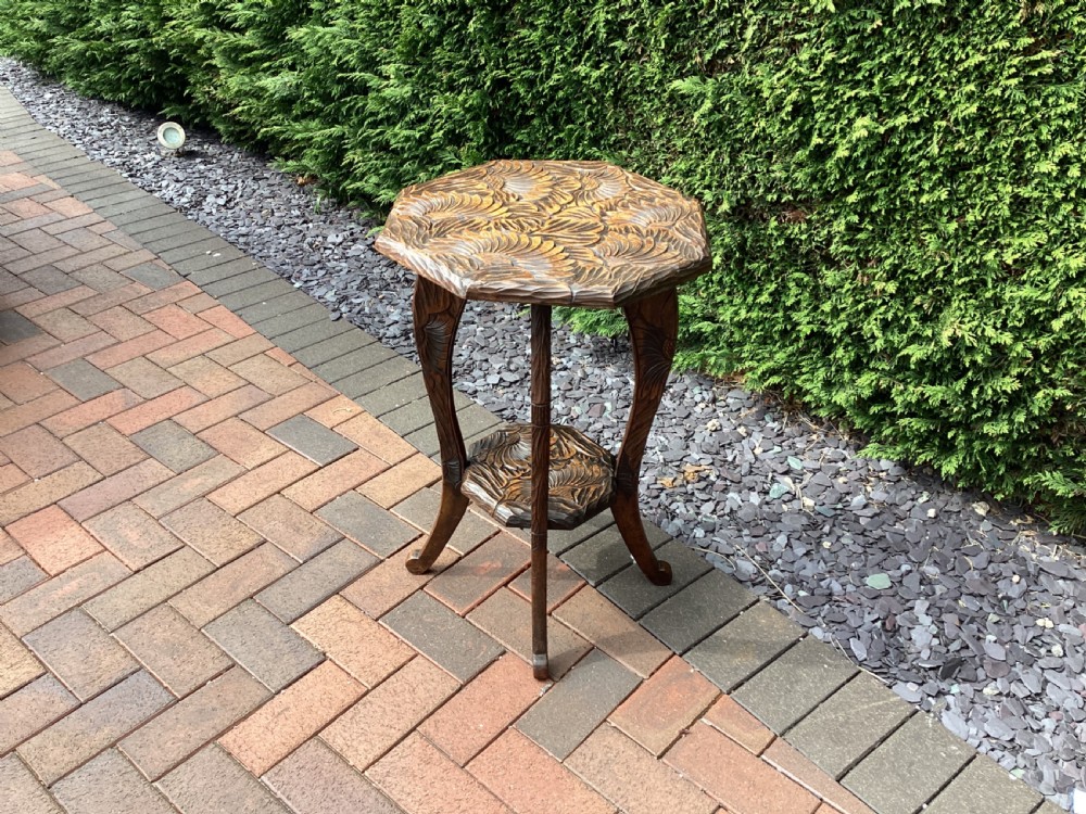 An antique dark wood octagonal side table featuring carved leaf patterns across the top surface, curved legs, and a lower tier shelf. View V