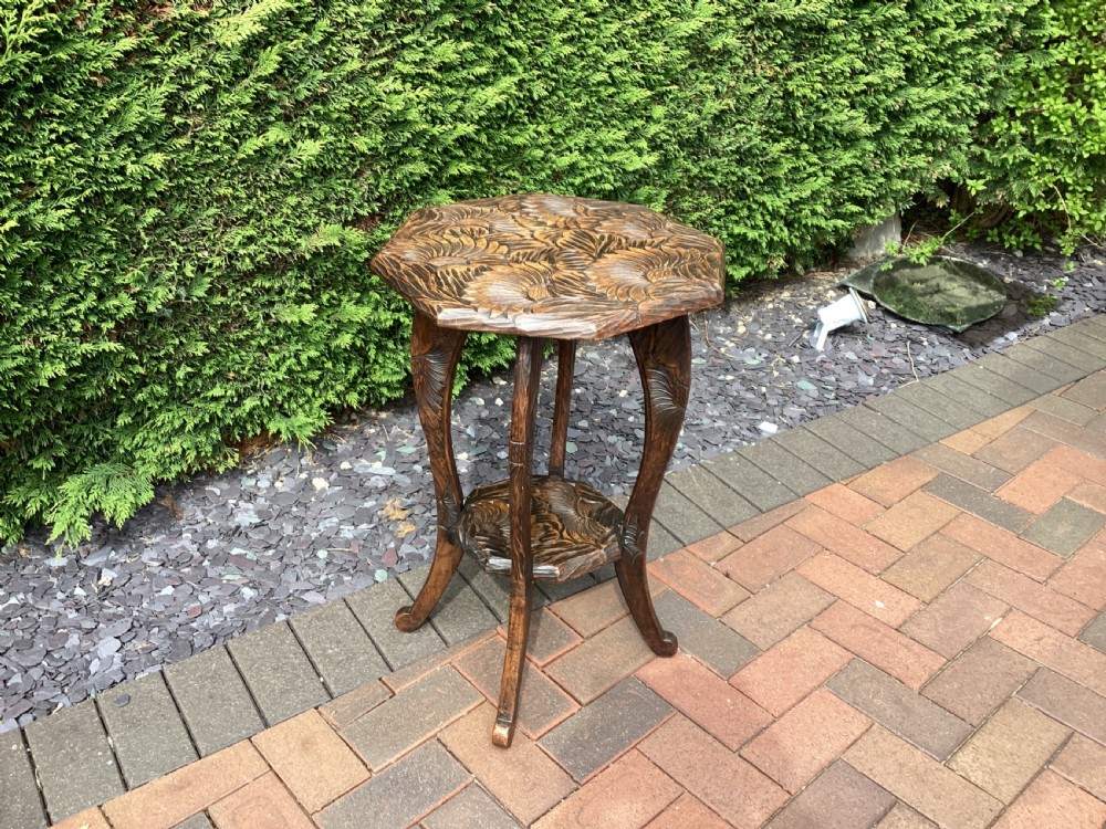 An antique dark wood octagonal side table featuring carved leaf patterns across the top surface, curved legs, and a lower tier shelf. View VI
