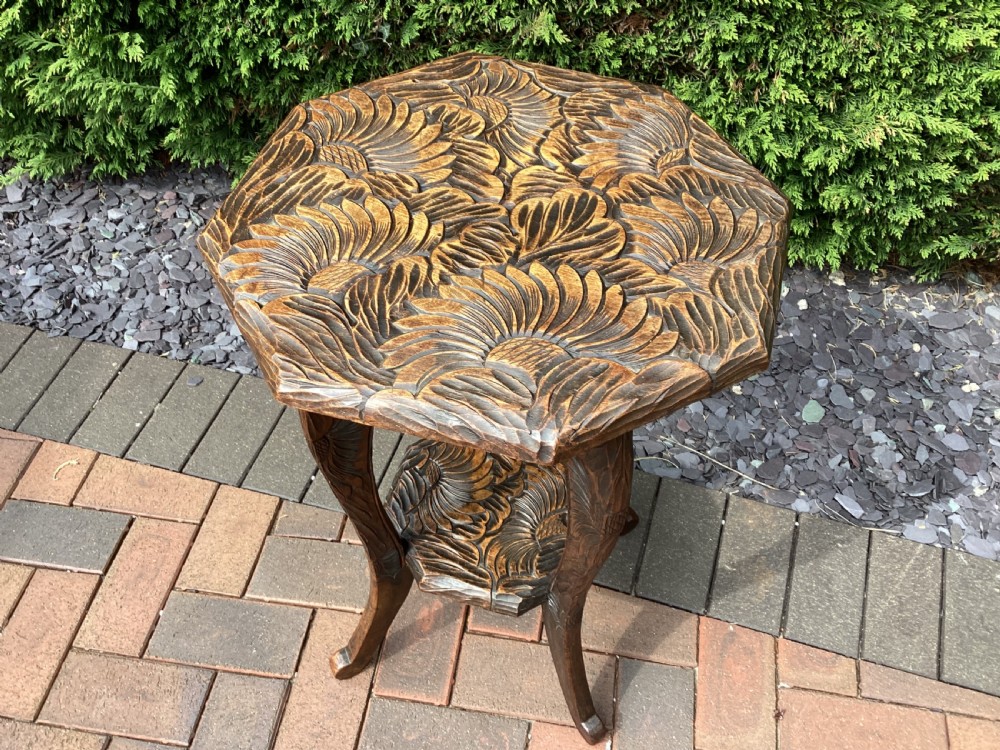 An antique dark wood octagonal side table featuring carved leaf patterns across the top surface, curved legs, and a lower tier shelf. View VII