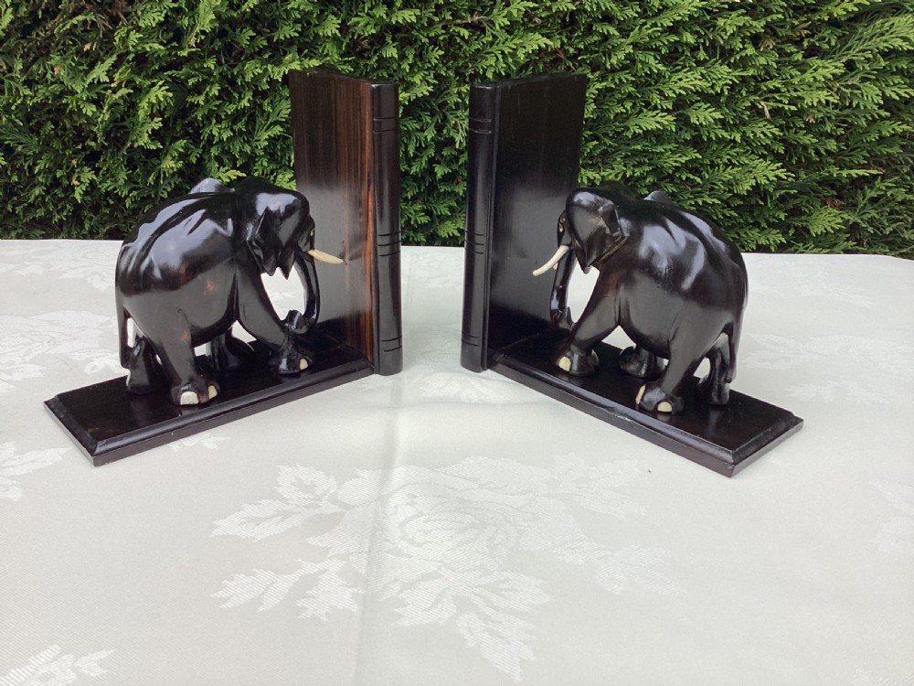 A pair of hand-carved dark coromandel wood elephant bookends featuring inlaid bone tusks and toes set on rectangular L-shaped bases. View V