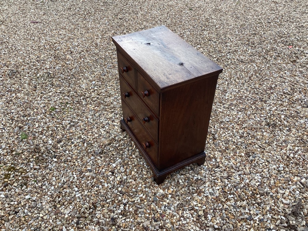 A small Georgian style miniature wooden chest of drawers featuring two short drawers over two long drawers with turned wooden knobs and bracket feet. View II