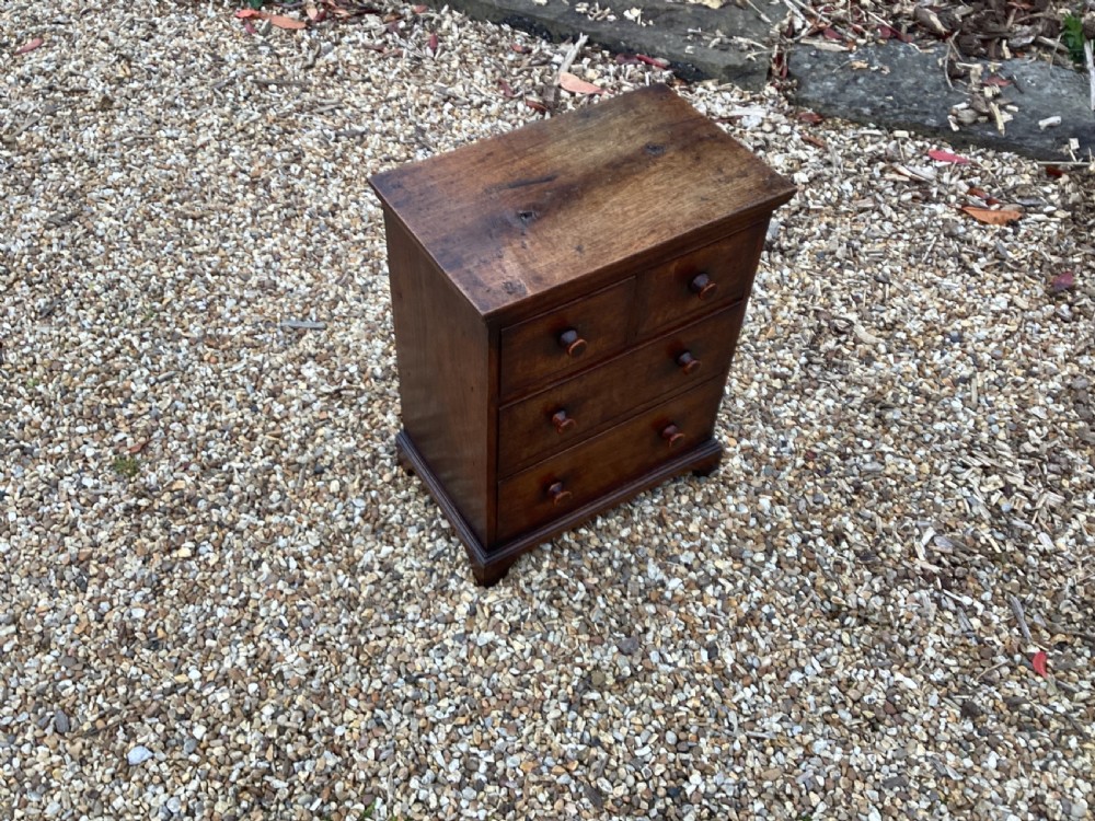 A small Georgian style miniature wooden chest of drawers featuring two short drawers over two long drawers with turned wooden knobs and bracket feet. View III
