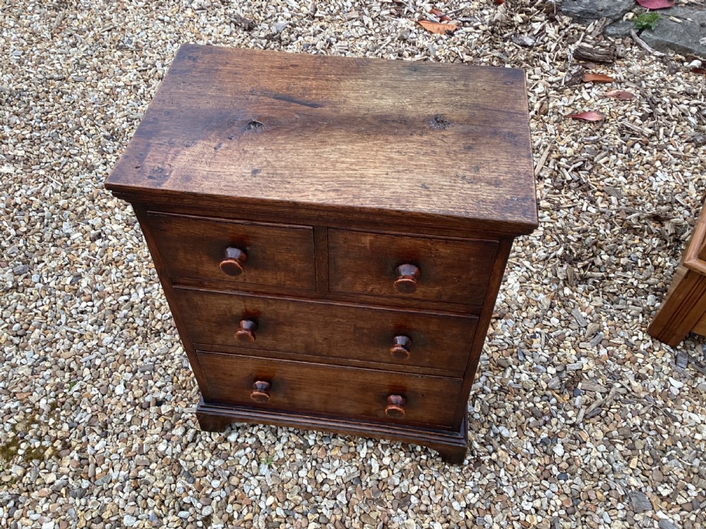 A small Georgian style miniature wooden chest of drawers featuring two short drawers over two long drawers with turned wooden knobs and bracket feet. View IV