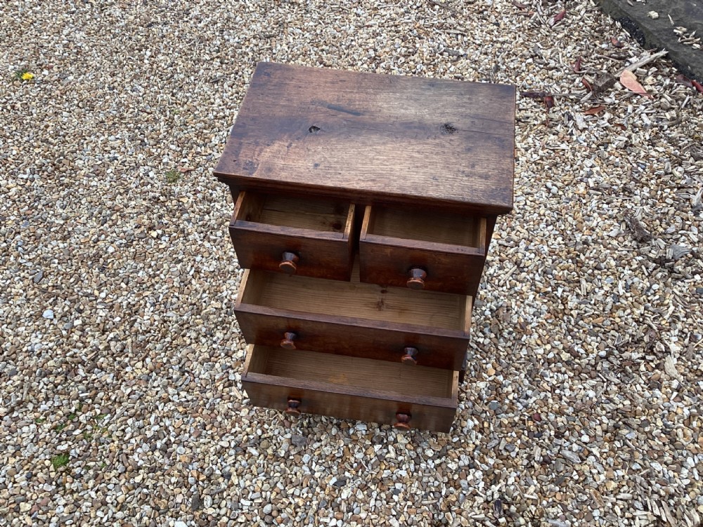 A small Georgian style miniature wooden chest of drawers featuring two short drawers over two long drawers with turned wooden knobs and bracket feet. View VII