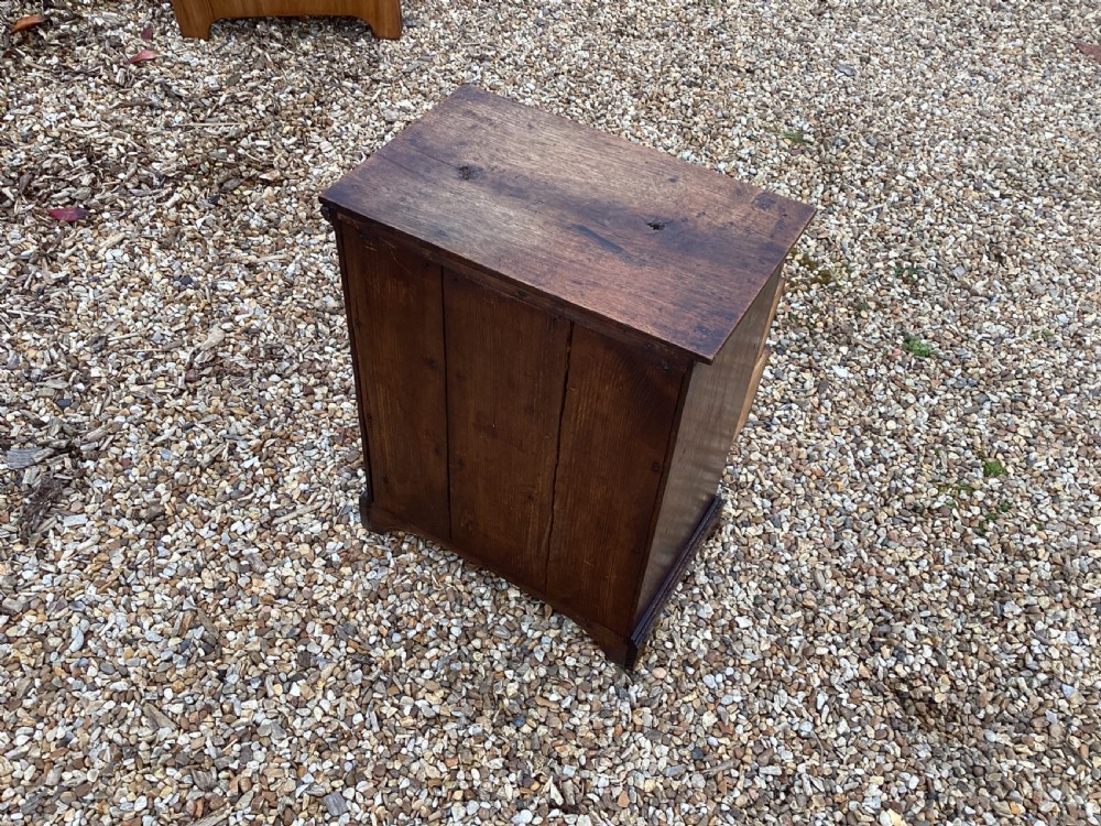 A small Georgian style miniature wooden chest of drawers featuring two short drawers over two long drawers with turned wooden knobs and bracket feet. View VIII